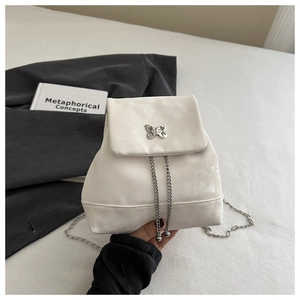 Detail of silver butterfly clasp and metal ball chains on white PU leather backpack