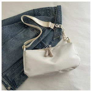Detail of white minimalist shoulder bag featuring wide strap and resin chain decoration