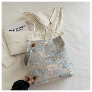 Gros plan détaillé du sac à bandoulière en jacquard floral avec pompon et perle élégants