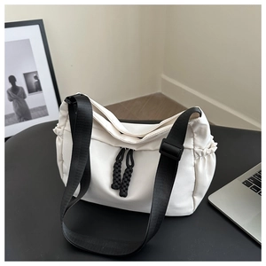 Close-up of white nylon tote with adjustable black strap and woven rope zipper pulls