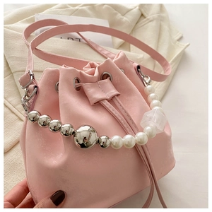 Detail of pink bucket bag featuring large pearl and silver metal ball chain strap