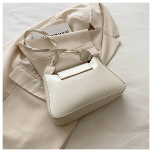 Detail of cream shoulder bag with woven knot strap on minimalist neutral background
