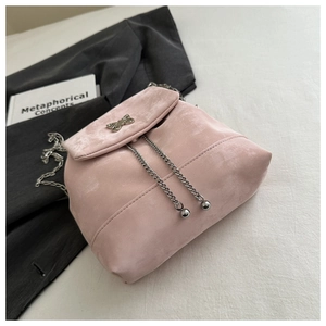 Detail of pink suede crossbody bag featuring silver butterfly buckle and metallic chain