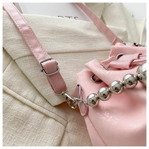 Detail of pink faux leather bucket bag featuring silver bead handle and metal hardware