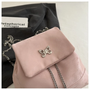 Close-up of pink velvet mini backpack featuring silver butterfly buckle and chain straps