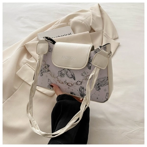 Detail of cream shoulder bag featuring butterfly prints and a silver floral chain strap