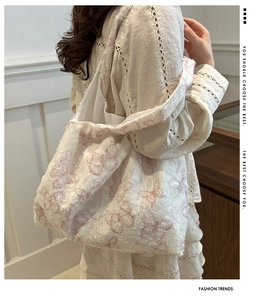 Detail of white canvas tote featuring pink butterfly embroidery and trendy fringed edges