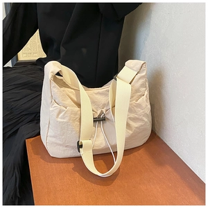 Close-up of durable cream nylon shoulder bag with pleated texture and adjustable drawstring