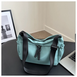 Detail of mint green nylon tote bag with braided zipper pull and wide black strap