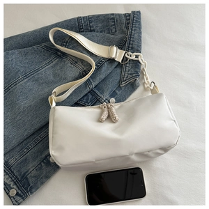 Detail of white rectangular crossbody bag with knot zipper pull and chain strap
