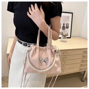 Pink drawstring bucket bag with silver butterfly charm and pearl chain details