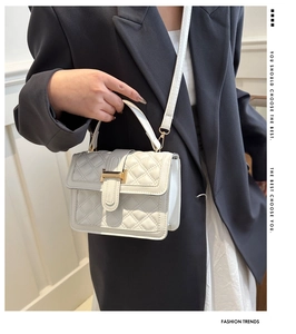 Detail of white quilted crossbody bag with gold metal clasp and leather strap