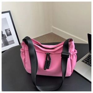 Macro shot of bright pink nylon bag featuring black adjustable strap and side pockets