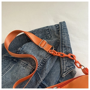 Detail of orange canvas bag with wide nylon strap, plastic chain and red zipper closure