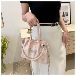 Detailed view of pink bucket bag featuring silver butterfly buckle and pearl chain handle