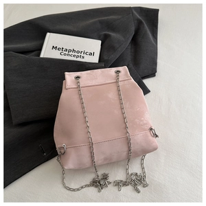 Detail of light pink suede backpack with silver butterfly chain strap and trapezoid design
