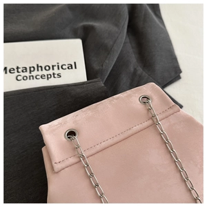 Detailed close-up of pink fabric bag showing metallic eyelets and silver chain strap