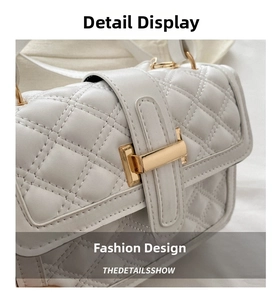 Close-up of white quilted leather texture and gold metal buckle on a square handbag