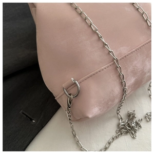 Detail of pink faux suede backpack showing silver chain strap and metal hook attachment