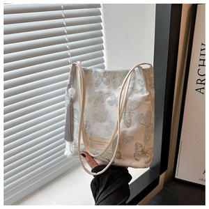 Détail du sac cabas brodé de papillons avec pompon décoratif et étiquette mode
