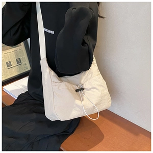 Detail of beige nylon crossbody bag with adjustable drawstring closure and large capacity