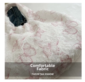 Detail of white lace tote with pink butterfly embroidery and soft feathered texture
