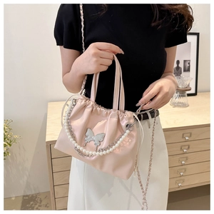 Pink drawstring bucket bag with pearl chain and silver butterfly charm detail view