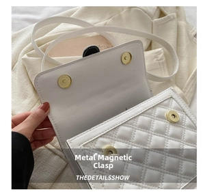 Detail shot of the white quilted crossbody bag featuring dual magnetic metal buckles
