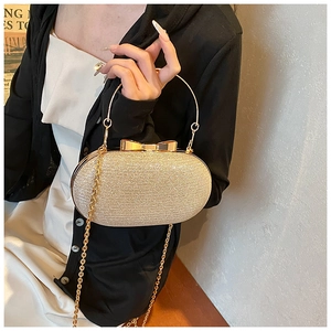 Champagne gold sequined clutch featuring a metallic bow clasp and circular handle grip