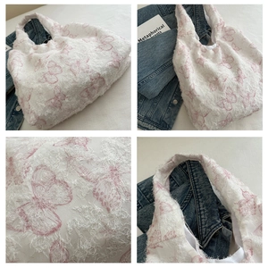 Close-up of white chiffon tote with feather texture and pink butterfly embroidery