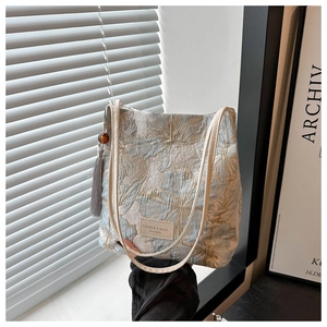 Détail du sac cabas en jacquard bleu avec logo en cuir et breloque à pompon gris