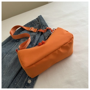 Detail of bright orange nylon crossbody bag with matching chain and woven zipper pull