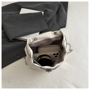 Top view of the white bucket bag interior showing smartphone, wallet and makeup items