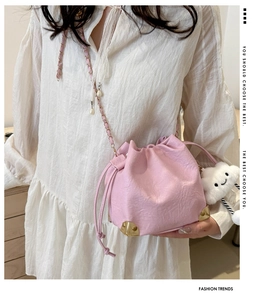 Pink drawstring bucket bag with gold corner protectors and a white cloud plush charm
