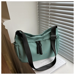 Detail of green nylon bag showing woven zipper pull and adjustable shoulder strap