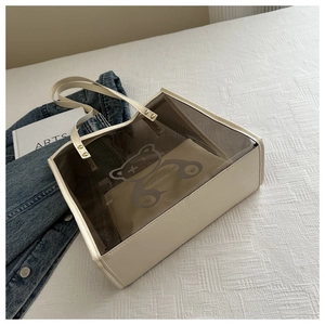 Vue détaillée du sac transparent avec motif d'ours et pochette intérieure sur drap blanc