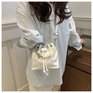 White pearlized leather bucket bag shown on shoulder with ornate beaded strap detail