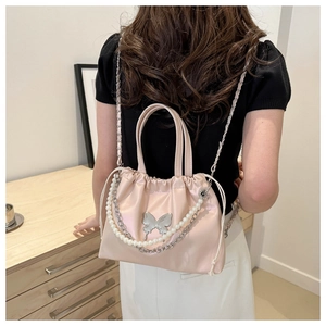 Detail view of pink satin bucket bag with pearl chain and butterfly metal ornament