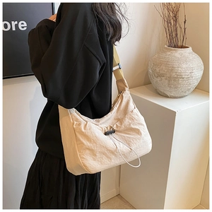 Detail view of the beige nylon crescent bag featuring adjustable straps and drawstring design