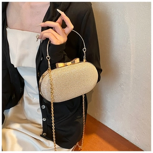 Champagne gold evening clutch with glitter texture and butterfly bow clasp on a table