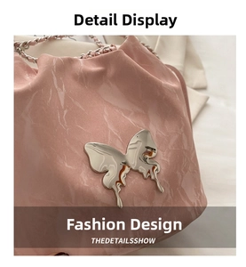 Gros plan du sac seau rose en cuir plissé brillant avec fermoir papillon argenté