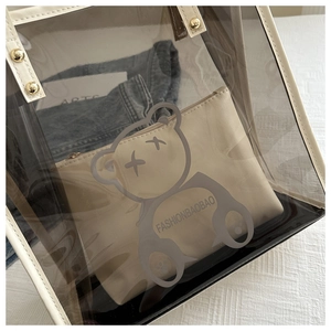 Détail d'un sac cabas transparent en PVC avec bordures en similicuir blanc et motif ours