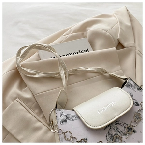 Detail of lavender butterfly print bag with silver chain and floral charm on a beige blazer