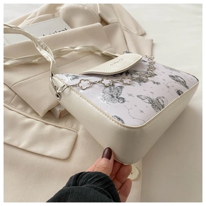 Detail of butterfly print crossbody bag with silver floral chain and fashion logo