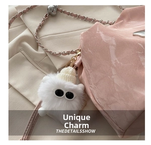 Gros plan sur un charm de sac monstre en peluche blanc avec bonnet sur sac rose