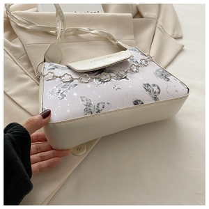 Detail of cream PU leather shoulder bag featuring purple butterfly print and floral metal chain