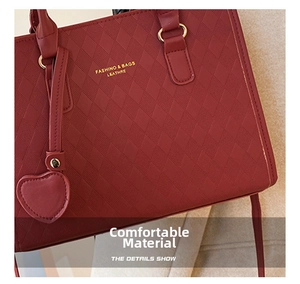 Detail of red quilted faux leather handbag with gold hardware and heart pendant