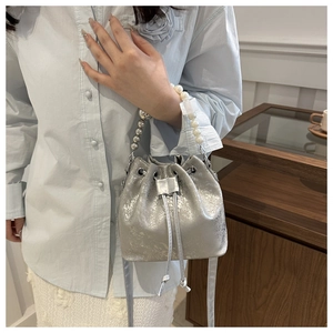 Détail du sac seau argenté à cordon avec une poignée en perles et billes argentées