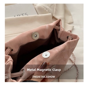 Gros plan du sac seau rose avec un fermoir magnétique en métal et une bandoulière chaîne
