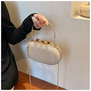 Detail of champagne gold glitter evening clutch with metal handle and bow clasp